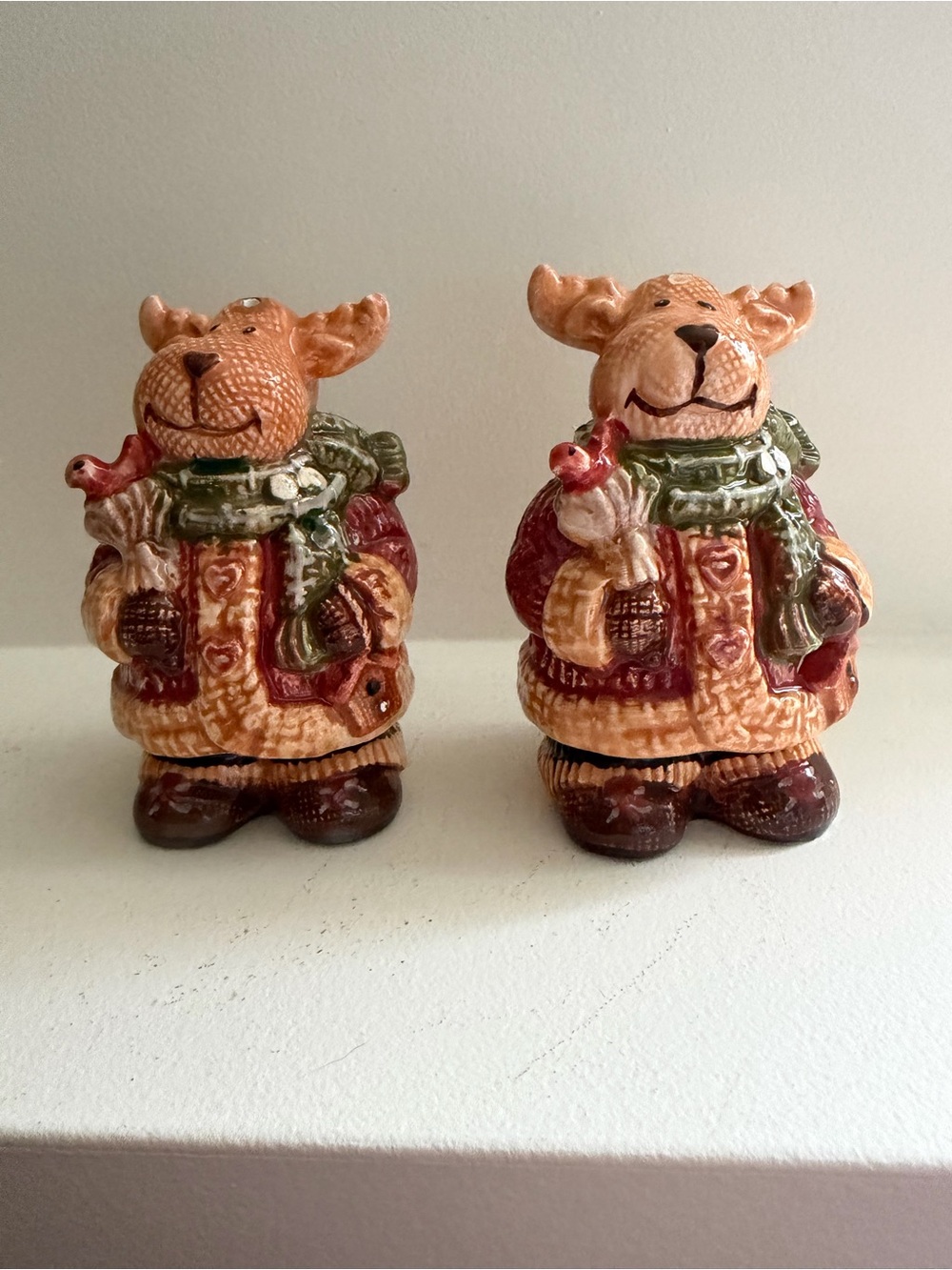 a pair of ceramic moose salt and pepper shakers featuring a winter holiday desig